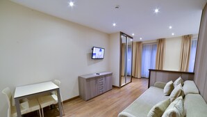 Une chambre moderne comprenant une table à manger, un canapé, un téléviseur, une armoire et un miroir.