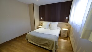 Une chambre à coucher avec un grand lit, des tables de chevet, une commode et un plancher en bois.