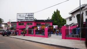 A pink building with a sign advertising a copy center, passport and photo prints, and internet services. - Sharp Guest House (Accra)