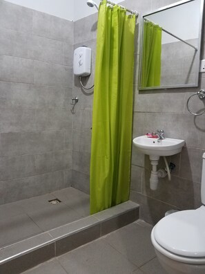 Un baño con ducha, lavamanos e inodoro.