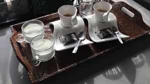 A tray with two cups of coffee, two glasses of milk, and a spoon on a table with a plant in the background. - BarandBed URT (Phunphin)