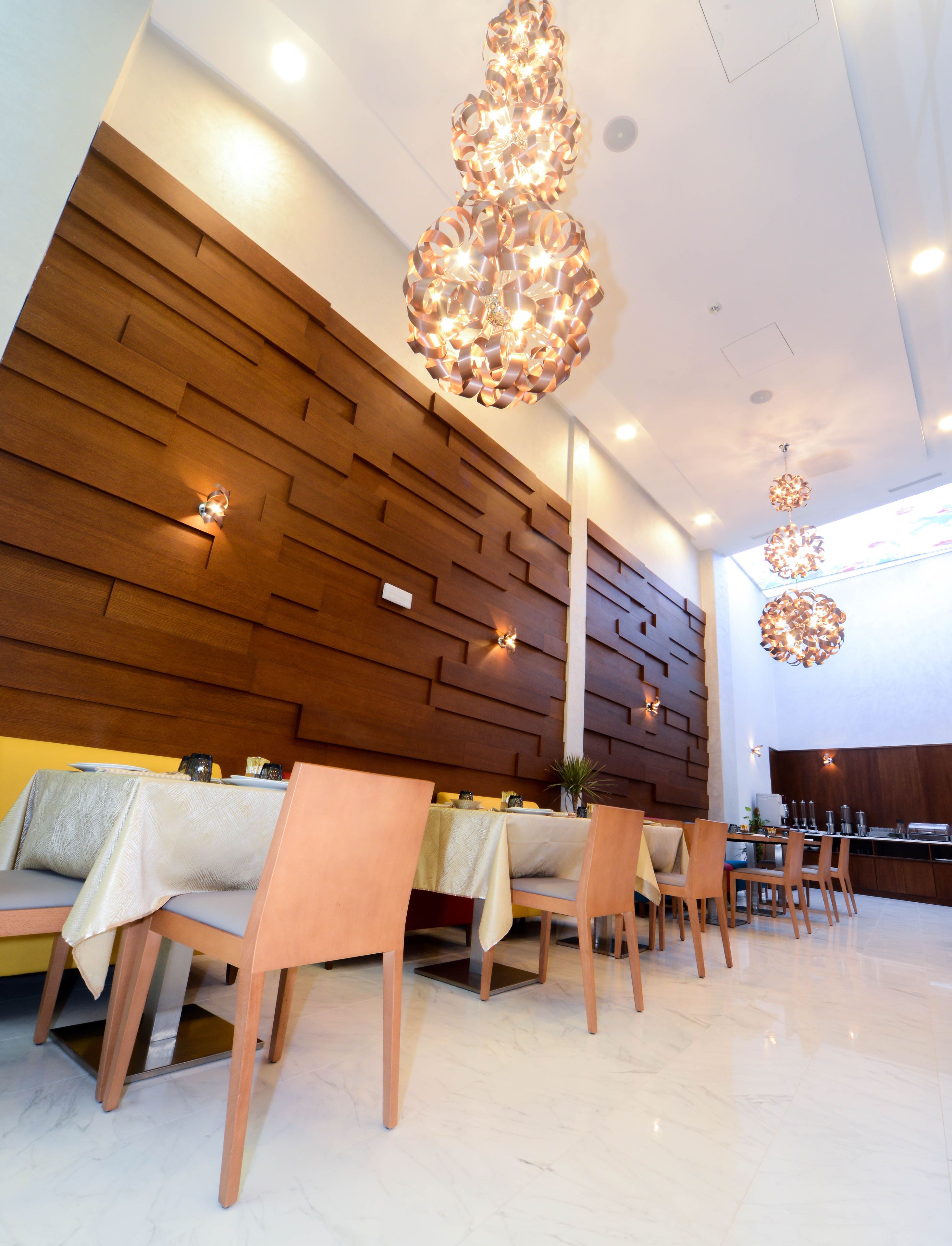 Un intérieur de restaurant moderne avec des murs lambrissés en bois, un sol en marbre et des luminaires contemporains.