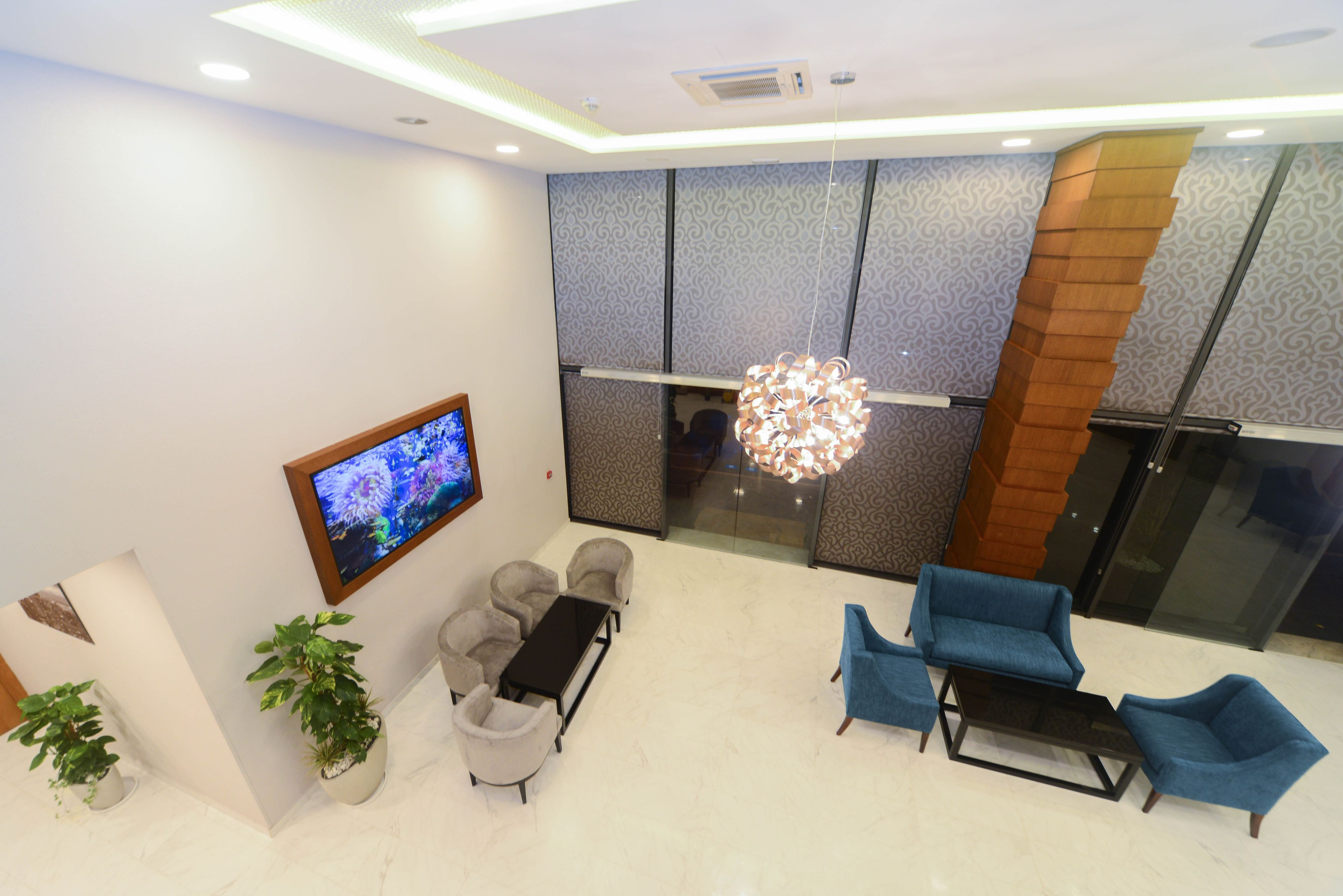 A modern lobby with a seating area, a television, and a decorative light fixture.