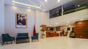 Een moderne lobby met een receptiebalie, zithoek en een vlag.