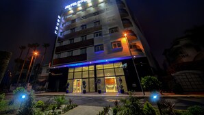 Een meerlaags hotel met een opvallend bord met daarop 'HOTEL & RESTAURANT' bij de ingang.