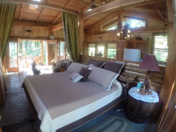Une chambre dans une cabane en bois, avec un grand lit, une petite table et une fenêtre.