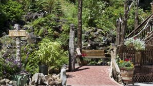 A pathway leading to a wooden bench surrounded by lush greenery and a rustic fence. - Lanzarotta Bed and Breakfast (Eugene)