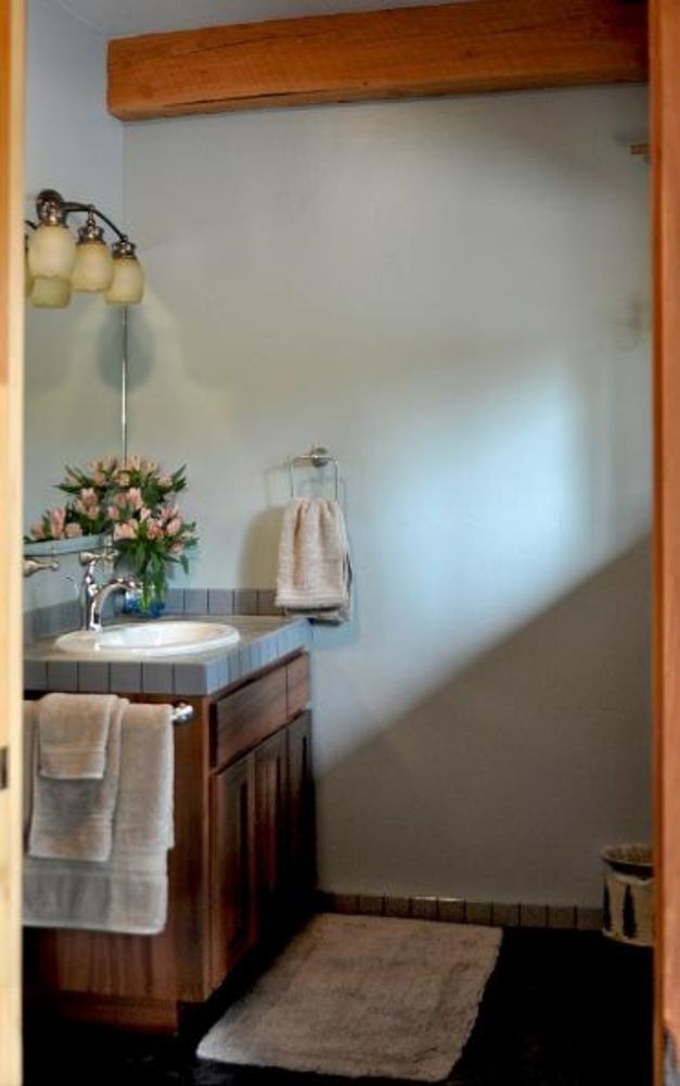 A bathroom with a wooden vanity, a sink, a mirror, and a towel rack.
