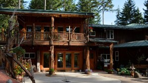 A wooden lodge with a balcony, a covered porch, and a clear driveway. - Lanzarotta Bed and Breakfast (Eugene)