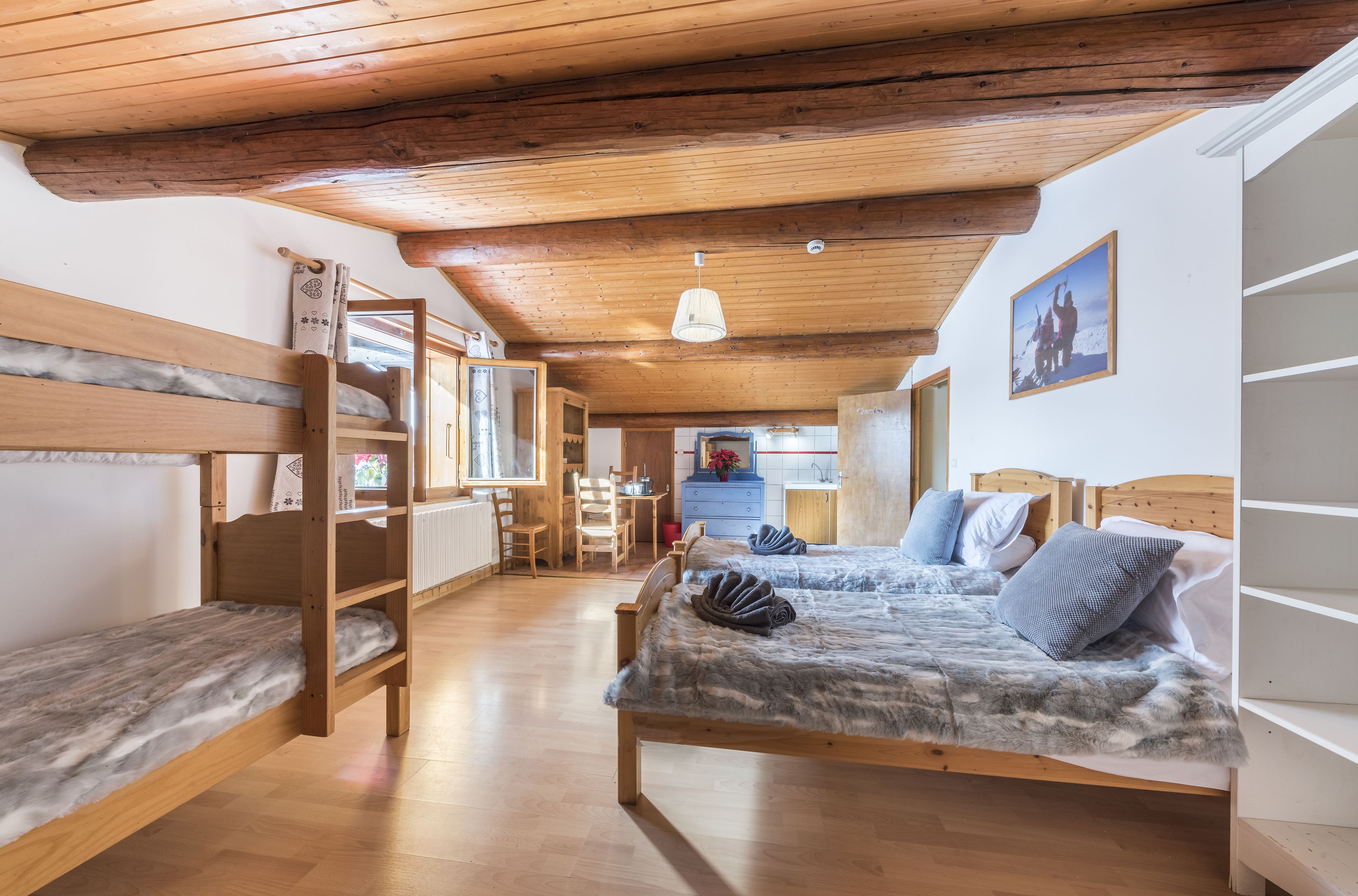 A cozy room with a bunk bed, a wooden ceiling, a desk, and a chair.