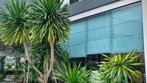 A modern building with a glass facade, a landscaped garden with various plants, and a visible staircase. - Marlin Hotel (Surat Thani)