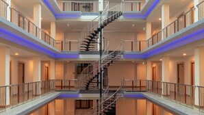 A multi-level atrium with a central spiral staircase, multiple balconies, and a glass ceiling. - Marlin Hotel (Surat Thani)