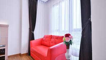 A modern living room with a bright red sofa, a glass coffee table, and a vase of flowers.