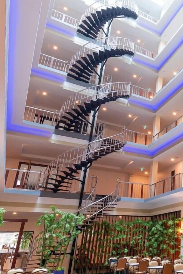 A multi-level interior with a central spiral staircase, multiple balconies, and indoor plants. - Marlin Hotel (Surat Thani)