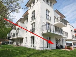 A large, multi-story building with balconies and a lawn in front.