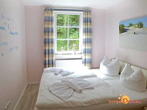 A bedroom with a bed, a window with curtains, a wall with writing, and a painting.