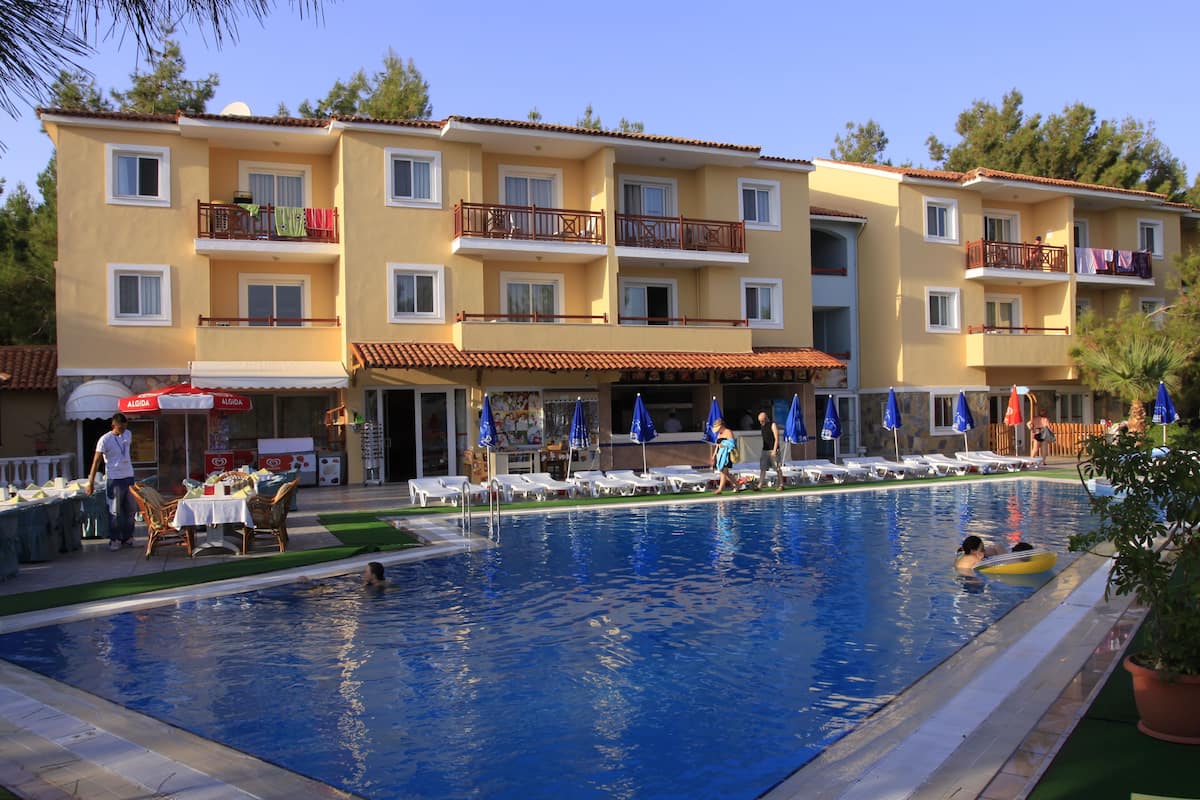 A hotel with a swimming pool, multiple balconies, and outdoor seating areas.