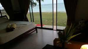A hotel room with a bed, a small table with a plant, and a view of the sea through large windows. - Heaven Beach Resort (Koh Samui)