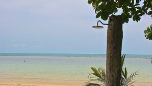 A beach with a tree and a concrete planter filled with pebbles. - Heaven Beach Resort (Koh Samui)
