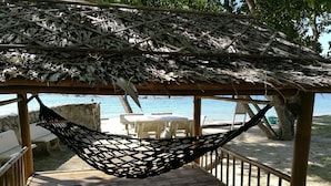 A hammock under a thatched roof structure with a view of the beach and ocean. - Heaven Beach Resort (Koh Samui)
