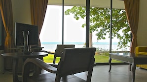 A room with a television, a dining table, and a view of the sea. - Heaven Beach Resort (Koh Samui)