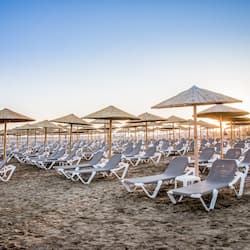 En la playa, sillas reclinables de playa, sombrillas, toallas de playa