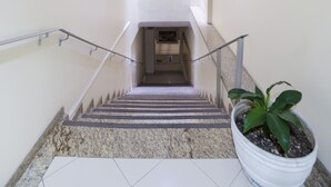 A staircase with a handrail, a potted plant, and a small window at the top. - Videiras Palace Hotel (Cachoeira Paulista)