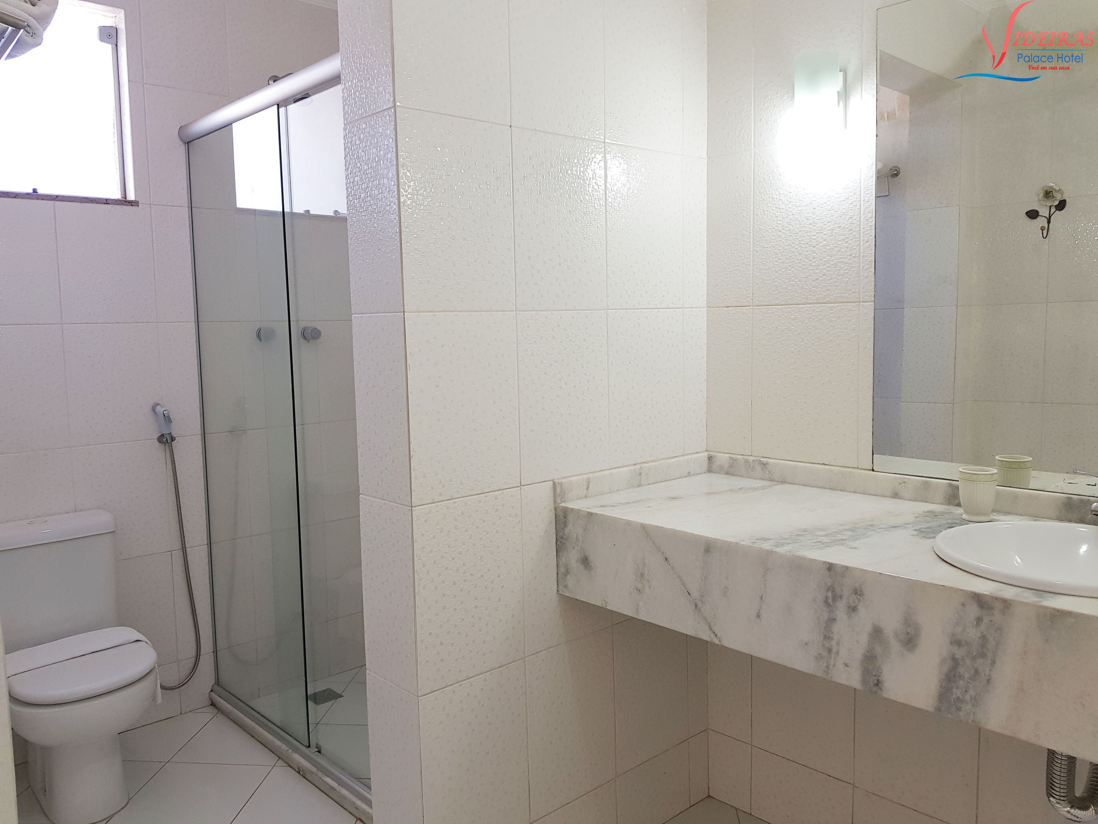 Une salle de bain avec une douche à parois de verre, des toilettes blanches et un lavabo en marbre.
