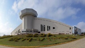 A modern building with a curved facade, a prominent cylindrical tower, and a landscaped area with trimmed bushes. - Videiras Palace Hotel (Cachoeira Paulista)