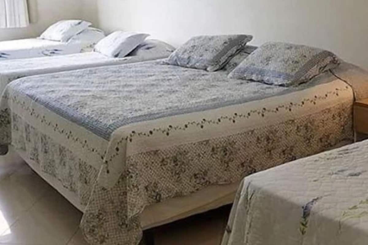 Een hotelkamer met twee bedden, een nachtkastje en een lamp.