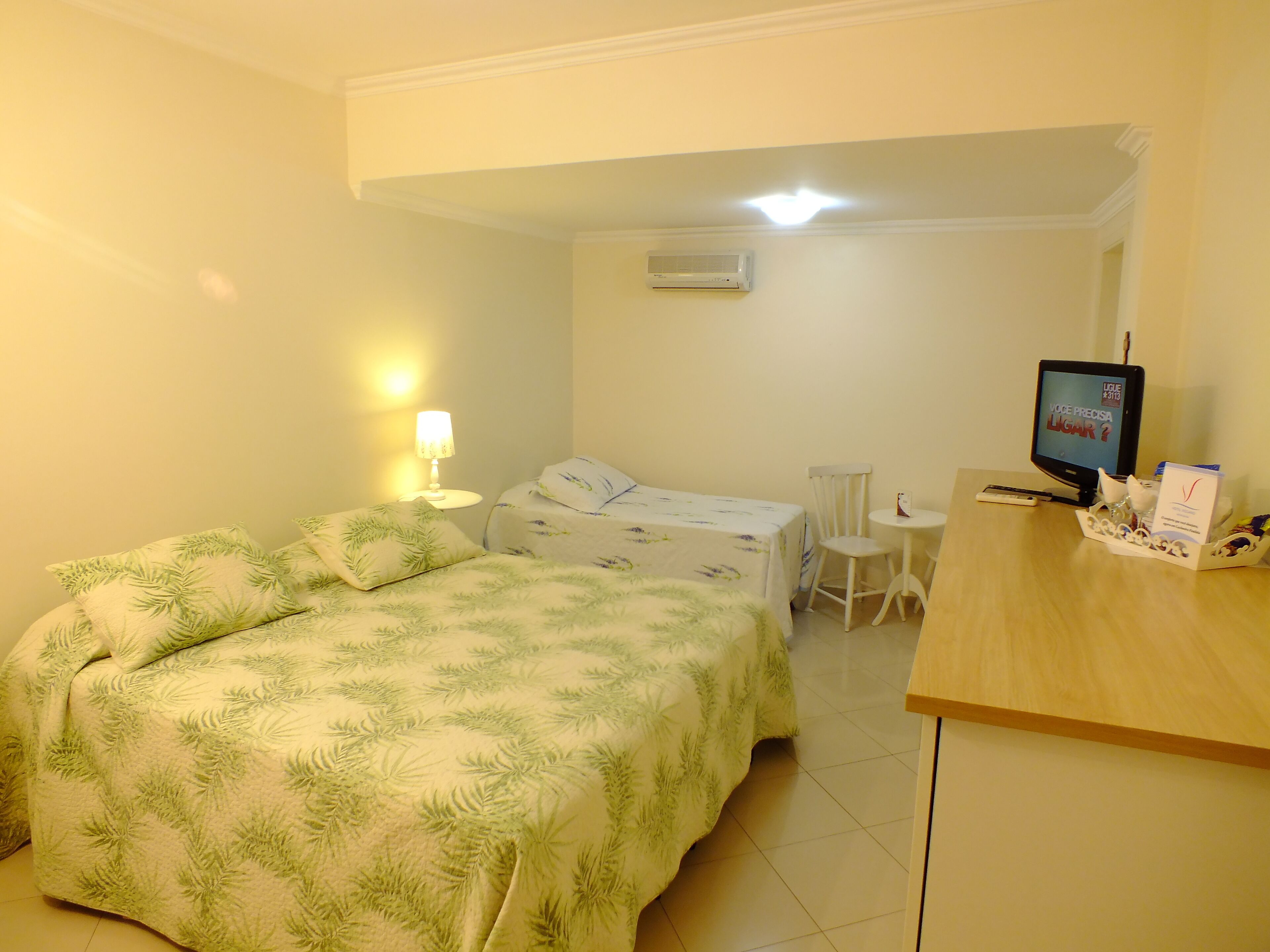 Ein Hotelzimmer mit Bett, Schreibtisch, Stuhl, Fernseher und Lampe.