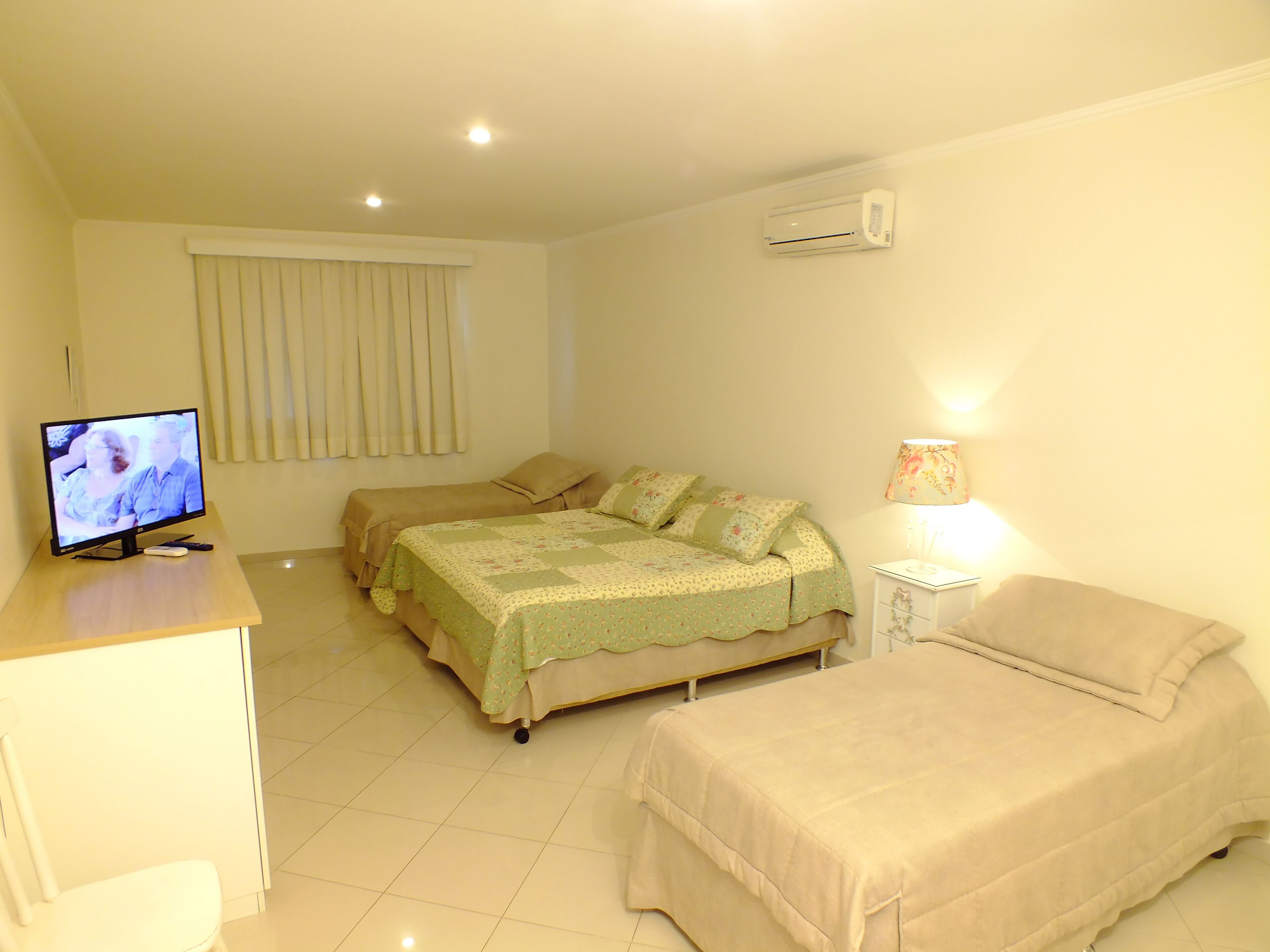 Une chambre avec deux lits, une télévision, une lampe et un climatiseur.
