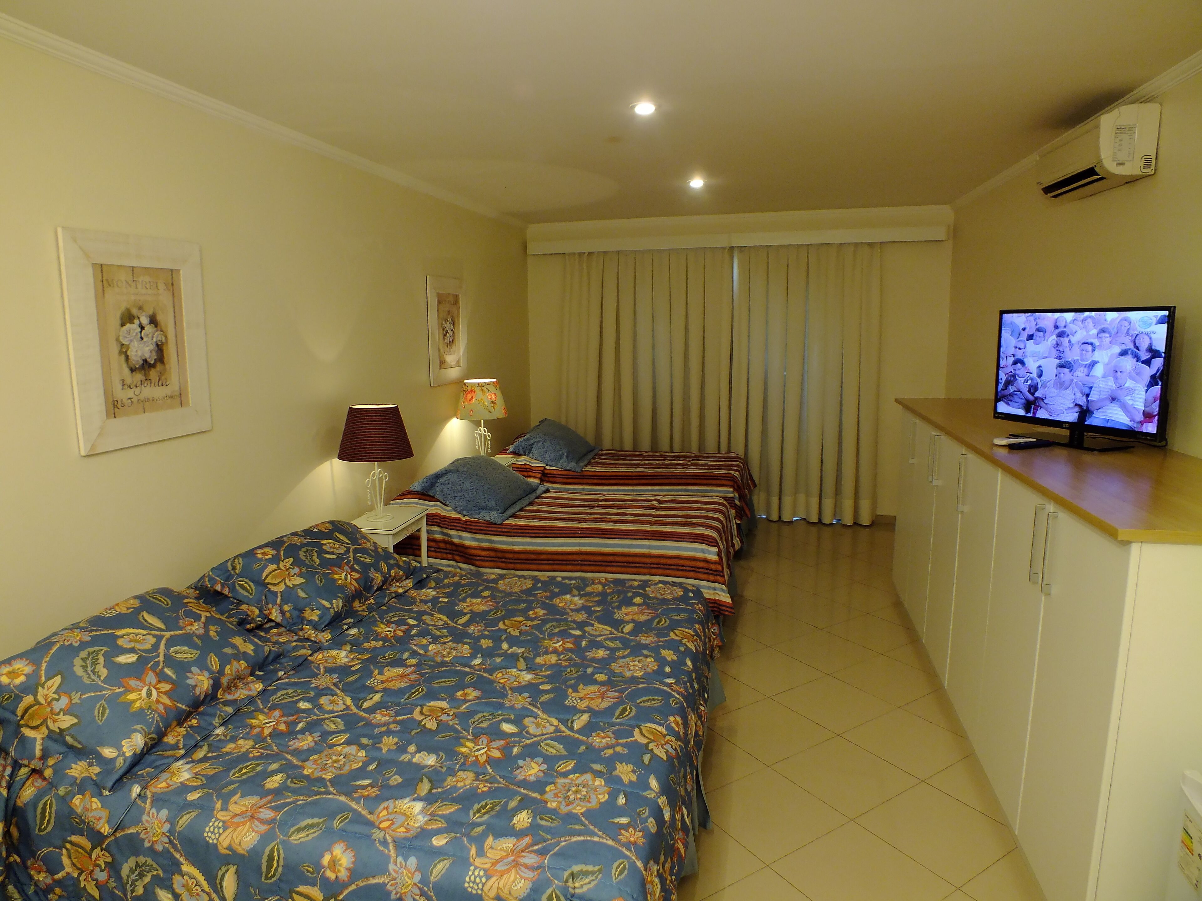 A hotel room with two beds, a television, and a cabinet.