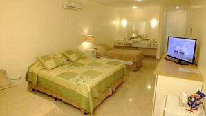 A hotel room with a large bed, a smaller bed, a desk with a television, and a bathroom with a mirror and sink. - Videiras Palace Hotel (Cachoeira Paulista)