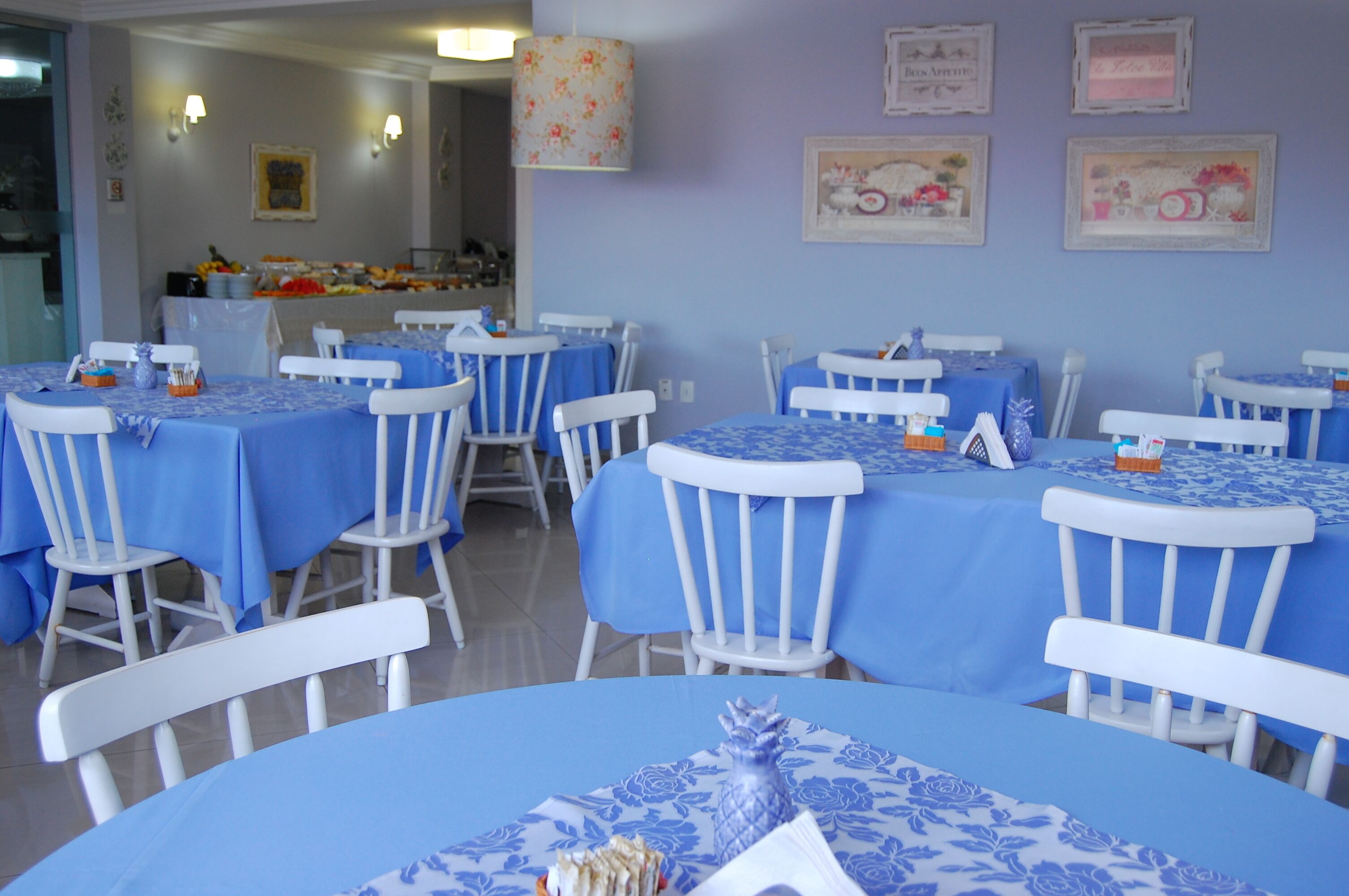 A dining area with round tables covered in blue tablecloths and white chairs.