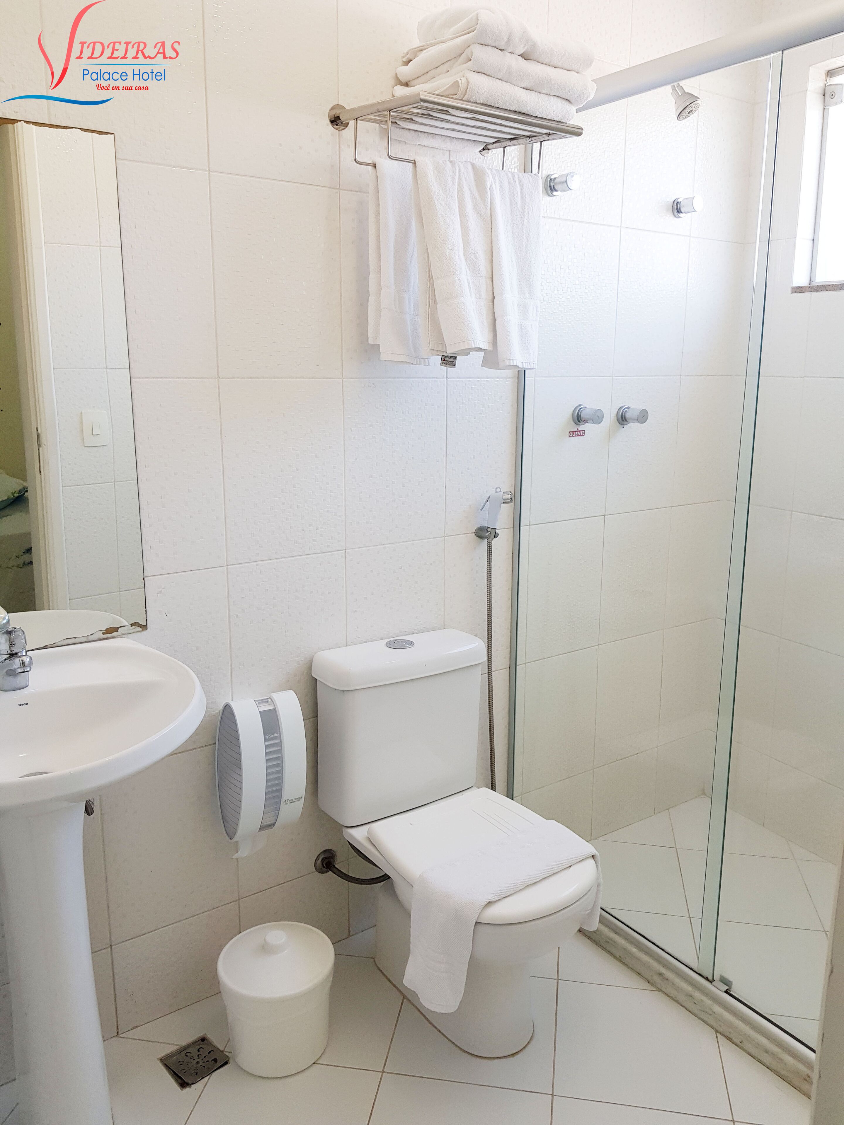 A bathroom with a toilet, bidet, sink, and glass shower enclosure.