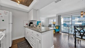 A modern kitchen with white cabinets, granite countertops, and a built-in island.