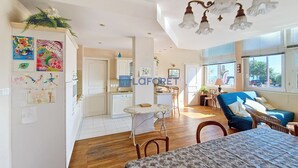 A spacious living area with a large bed, a dining table, and a kitchen in the background.