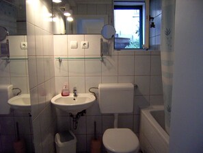 A bathroom with a toilet, sink, and bathtub. There is a window above the toilet, and a mirror on the wall. - newly renovated house, fantastic terrace with view of the sea (Dalmatien)