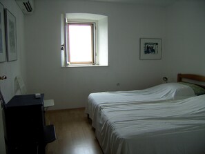 A small, sparsely furnished room with two beds, a desk, and a window providing natural light. - newly renovated house, fantastic terrace with view of the sea (Dalmatien)