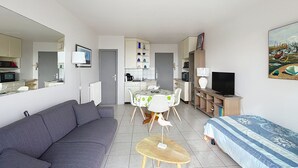 Un espace de vie compact comprenant un canapé, une table à manger avec des chaises, un téléviseur et un tableau accroché au mur.