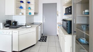 Une cuisine compacte avec des meubles blancs, un four à micro-ondes, une machine à café et un égouttoir à vaisselle.