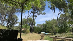 A patio area with a stone bench and a chair, surrounded by trees and a clear sky. - Near Aix-en-provence, country house, with pool without vis-à-vis (Aix-en-Provence)