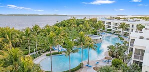 A resort with a large pool, palm trees, and a view of the sea. -  Mariner's Club 606 • Spacious 4/4 • Pools, Marina & Pickleball (Key Largo)