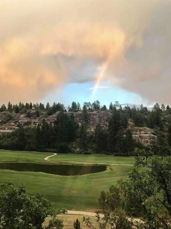 A golf course with a pond, trees, and a rocky hill in the background. - Love Nest in Durango (Durango)