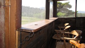 A rustic wooden cabin with a bar area and several wooden chairs. - Ranch House in the Elkhorn Mountains (Clancy)