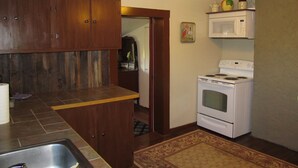 A kitchen with wooden cabinets, a white stove, and a microwave. - Ranch House in the Elkhorn Mountains (Clancy)
