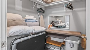 A compact, well-organized room with a bed, a small bench, a mirror, and a storage bin. - Captain's Quarters Riverfront #1 (Nashville)