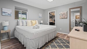 A neatly arranged bedroom with a large bed, bedside tables, a desk, and a mirror. - Captain's Quarters Riverfront #1 (Nashville)