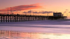 A pier extending into the water with a building at the end. - Newly built + Ocean View + Steps to Sand (Newport Beach)